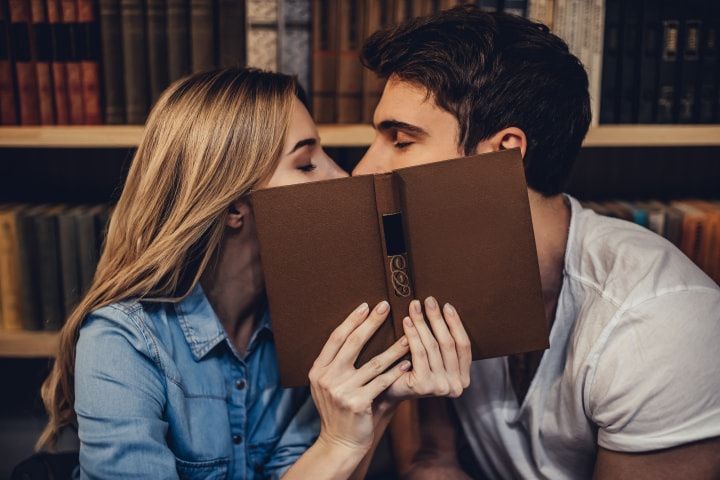 chica y chico tapándose con un libro el beso
