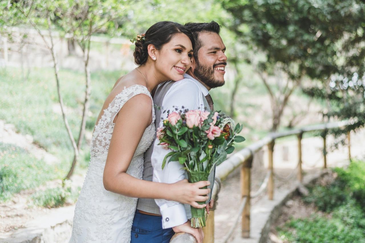 Novios el día de su matrimonio, la novia sostiene su bouquet de bodas con flores naturales