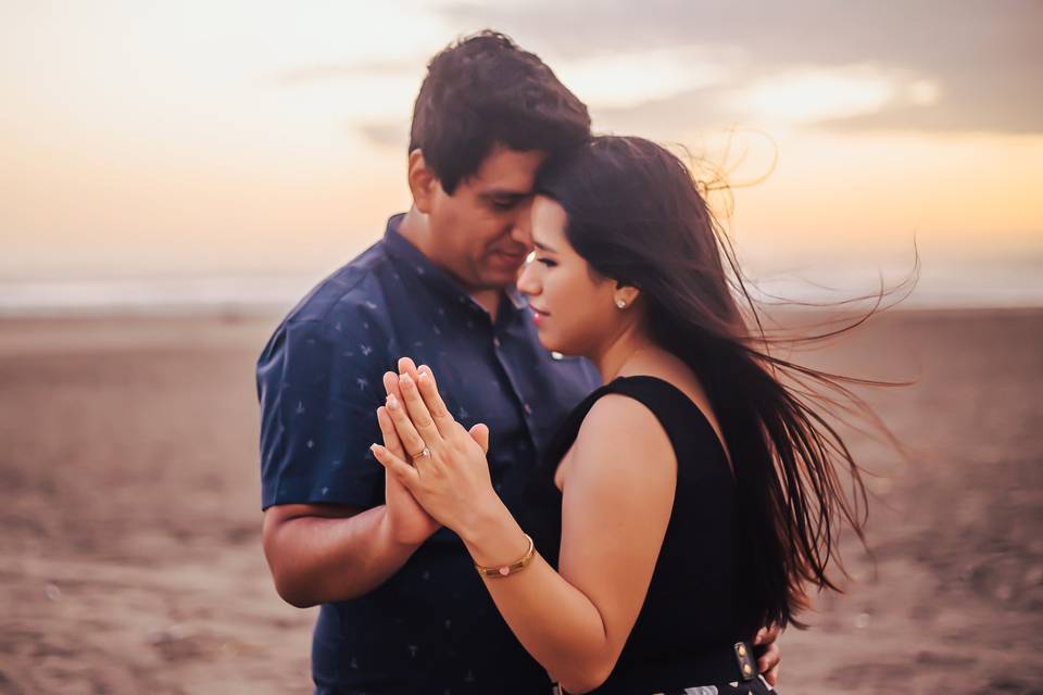 pareja con las manos juntas en la playa de Lima durante el atardecer
