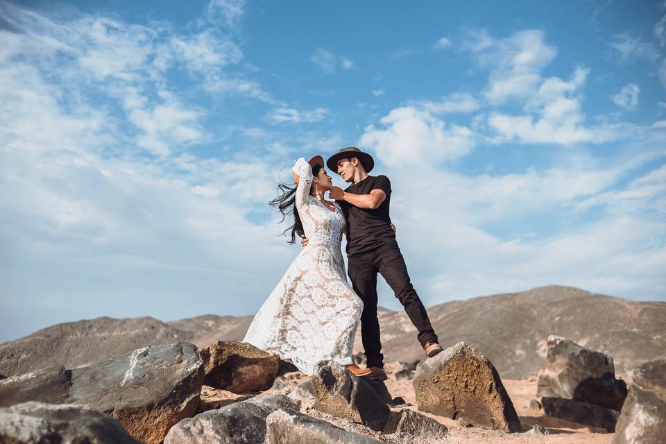pareja de novios abrazados románticos con sombreros y al aire libre entre las montañas