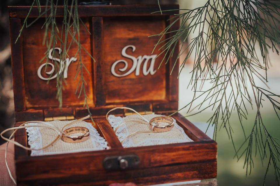 cofre de madera con dos aros de matrimonio sobre cojines pequeños y en la contra tapa escrito Sr y Sra