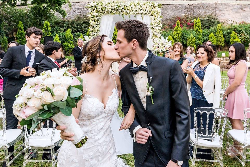 Pareja de recién casados dándose un beso a la salida de su ceremonia