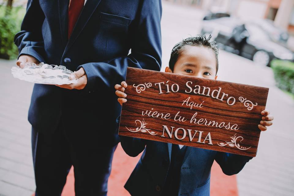 Niño o pajecito de boda con letrero anunciando la entrada de la novia