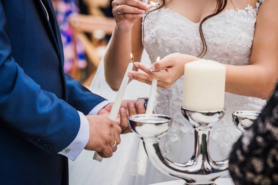 manos de la novia y el novio encendiendo las velas en su boda