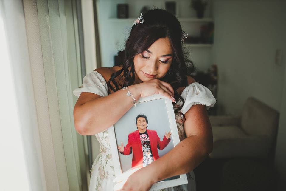 Novia sosteniendo un portarretratos con la foto de su padre recordando a su padre fallecido como homenaje