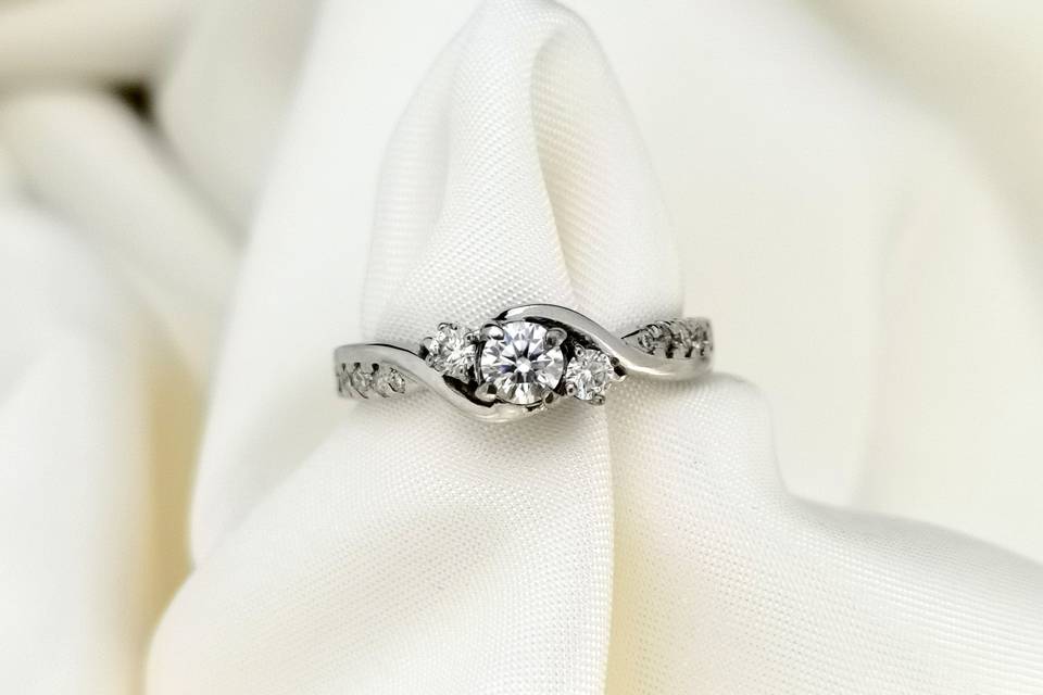 anillo de compromiso en plata con un diamante central y otras pequeñas piedras alrededor
