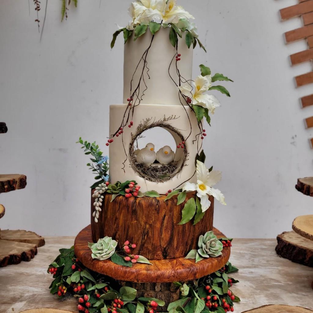 torta de matrimonio para primavera con flores y adorno de nido en la parte central del pastel