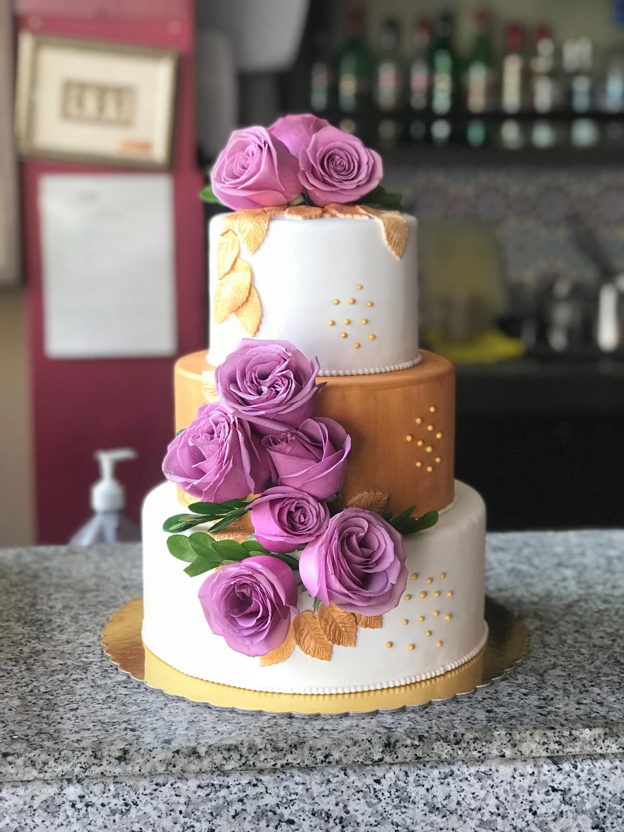 torta de matrimonio elegante e tres pisos con flores naturales y tonos dorados
