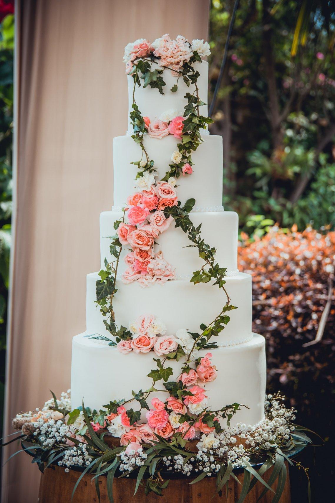 torta de matrimonio para primavera con flores rosadas y follaje verde