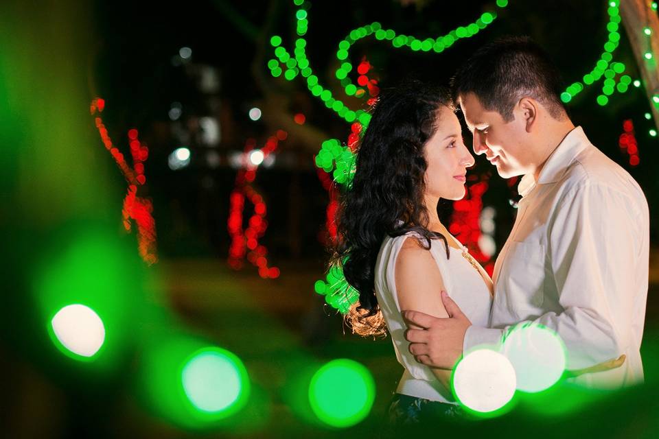 chico y chica abrazados mirándose a los ojos delante de luces verdes y rojas