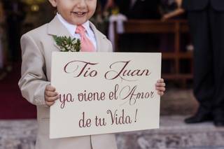 niño sonriendo con terno llevando un letrero que dice tío Juan ya viene el amor de tu vida