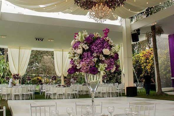 Mesa con mantel blanco y arreglo floral alto