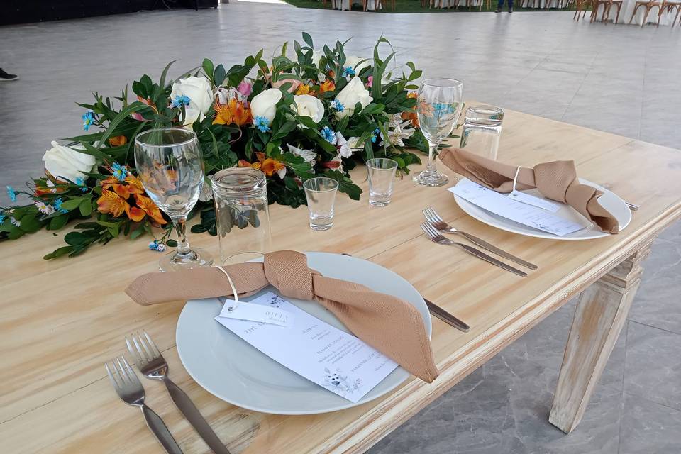Mesa de novios cona rreglo floral de colores y mesa de madera