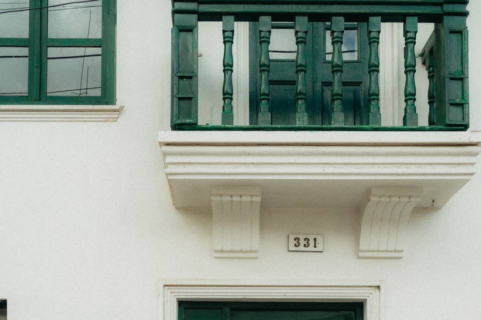 Novia recargada en la puerta de una casa blanca