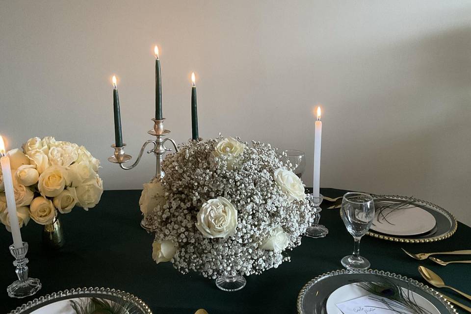 Mesa con vajilla blanca, mantel verde y arreglo floral blanco