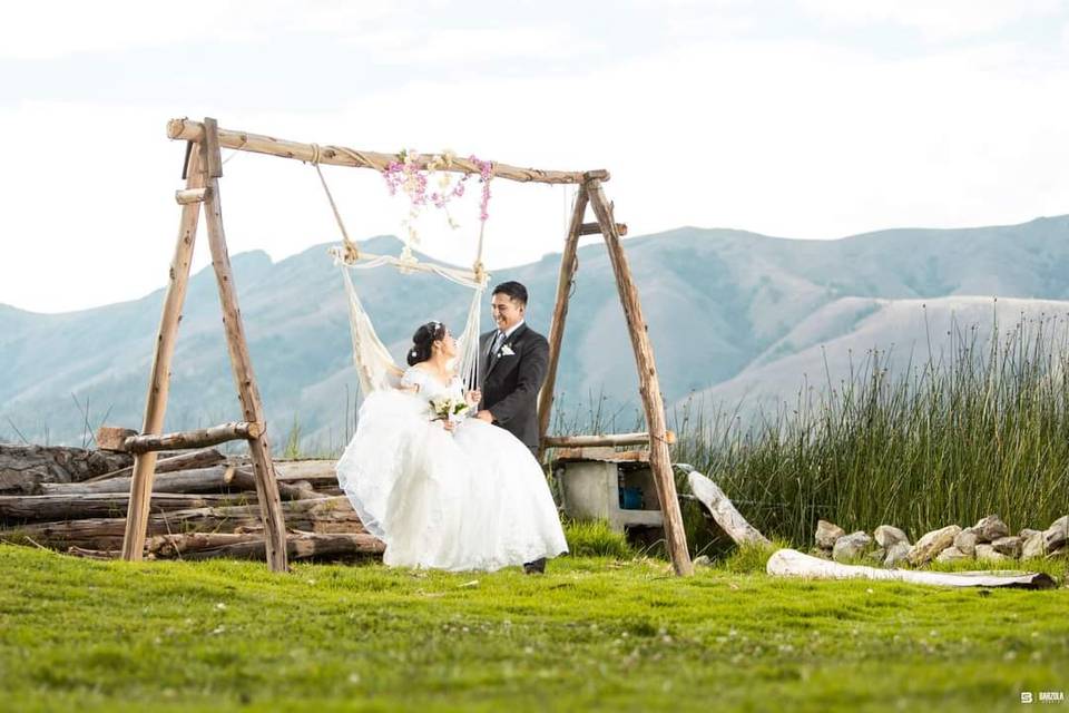 Pareja en un columpio en un campo frente a las montañas