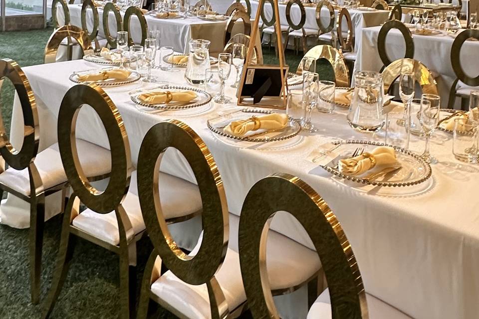 Mesa con mantel blanco y sillas doradas
