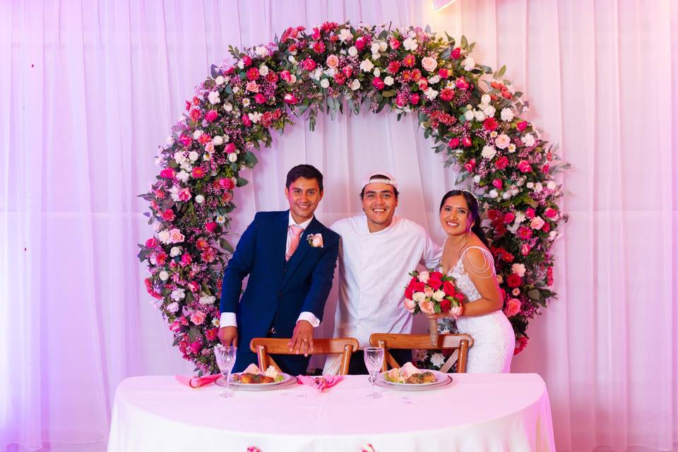 Novios felices posando en la mesa con el chef